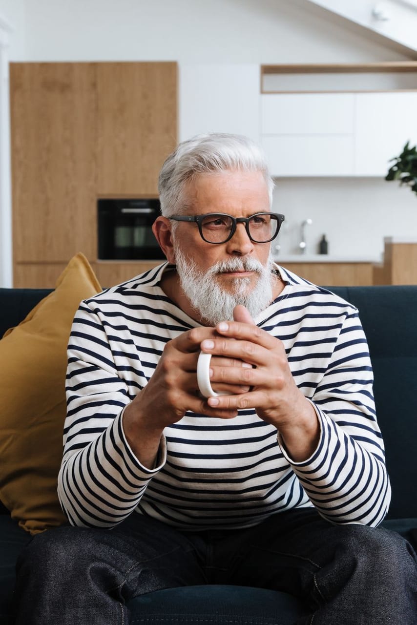 An older man with a cup of coffee at home