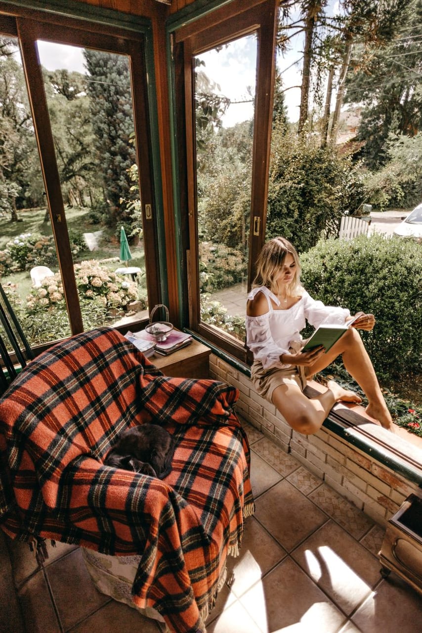 Reading by the window, wrapped in a blanket