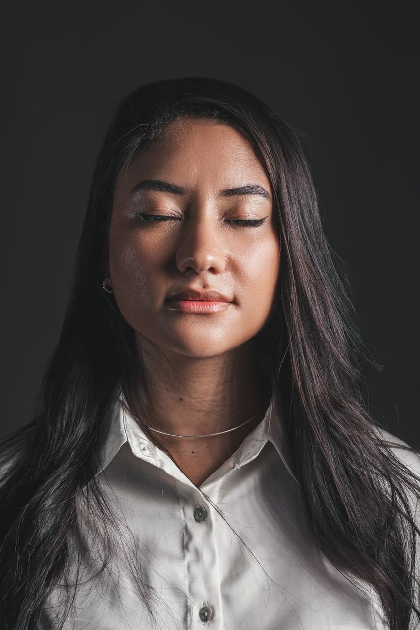 A person with eyes closed, hand to chest