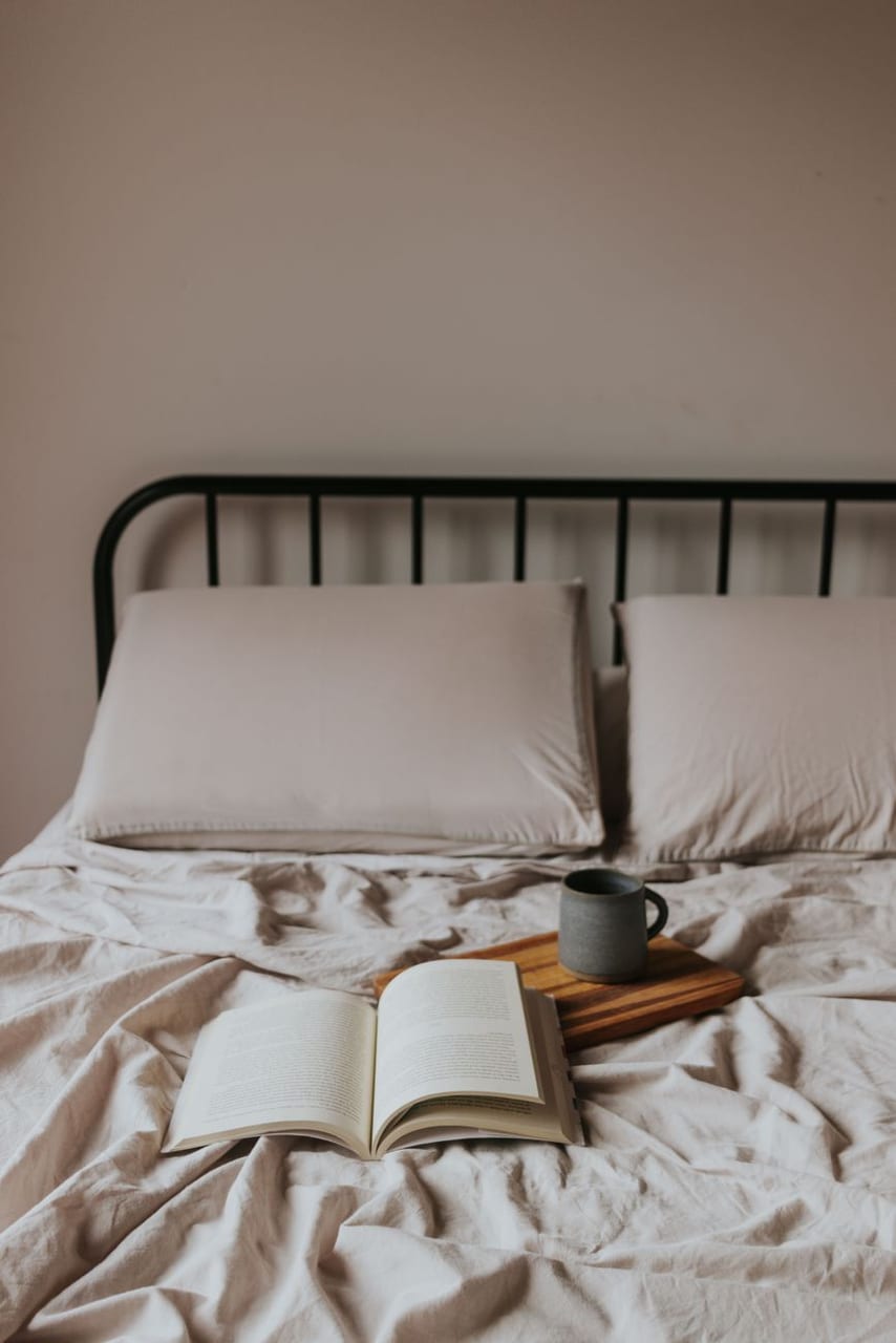 A bed with an open book and coffee, morning