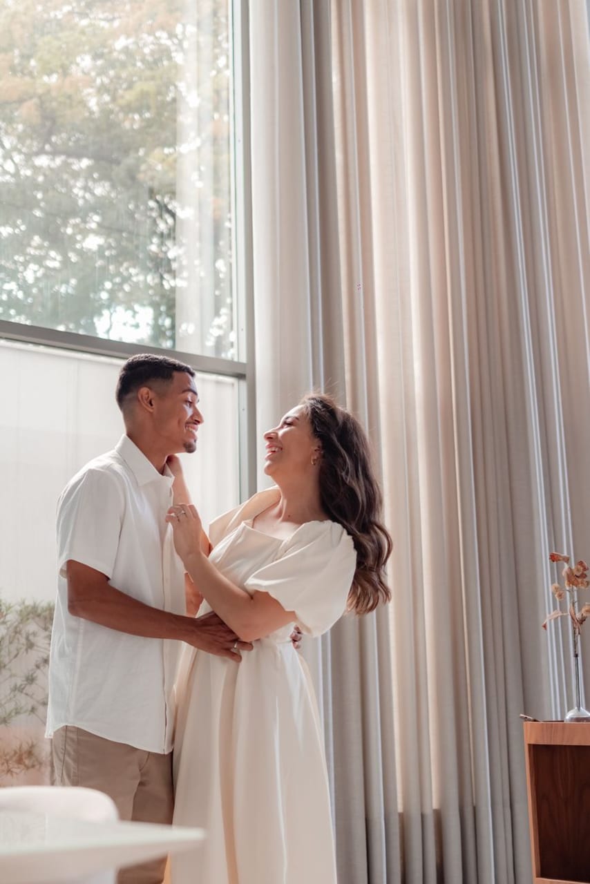 A couple laughing together by the window