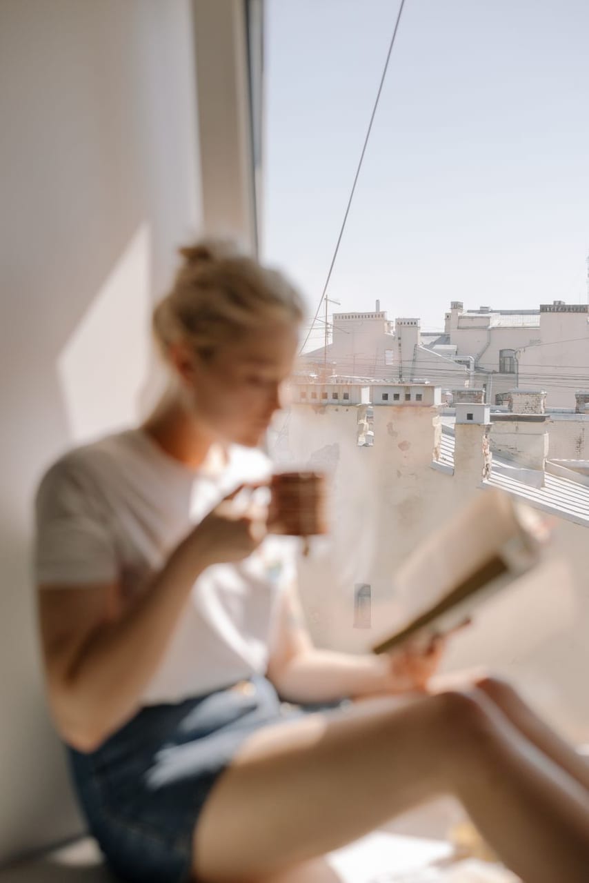 A woman reading by the window with coffee
