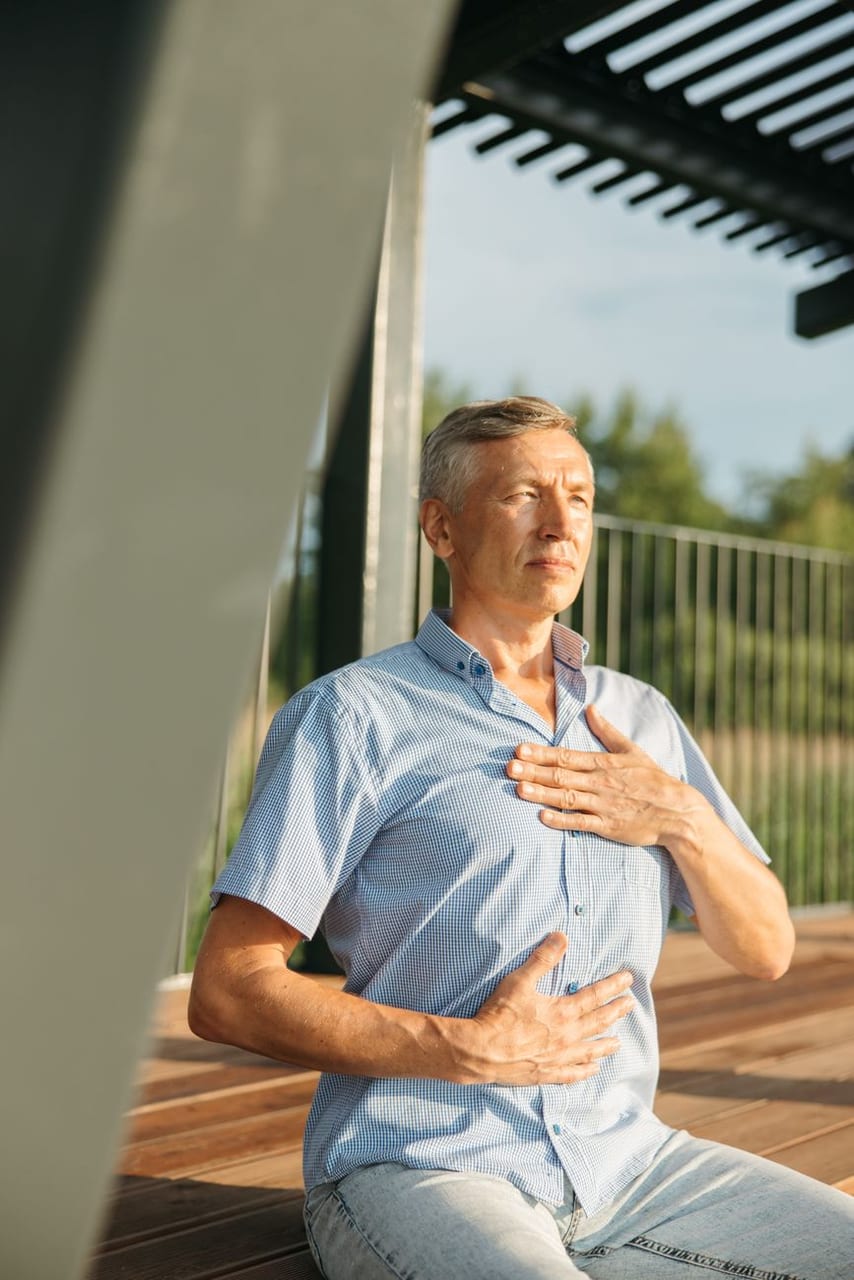 An older man, a hand on his chest, breathing