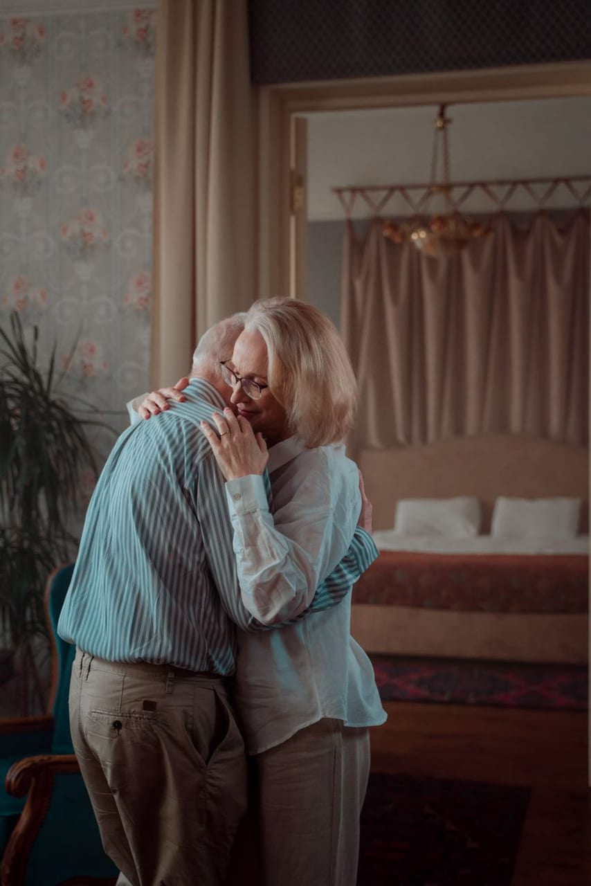 An older couple holding each other, cheek to cheek